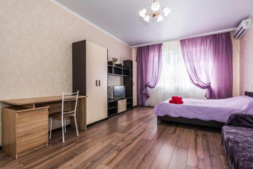 1 dormitorio con cama, escritorio y cortinas moradas en Люкс на Гаражной почти в центре, en Krasnodar