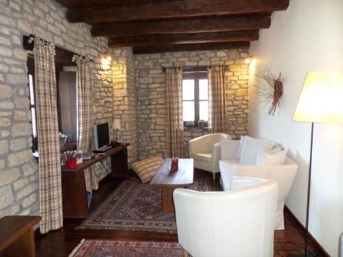 a living room with white furniture and a stone wall at Arhontiko Aristis in Aristi