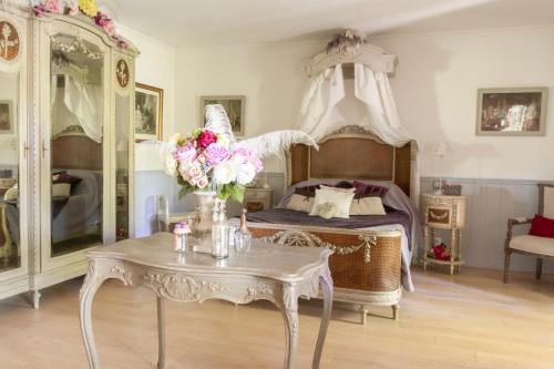 a bedroom with a canopy bed and a table with flowers at Le Bonheur à la Campagne in Lesmont