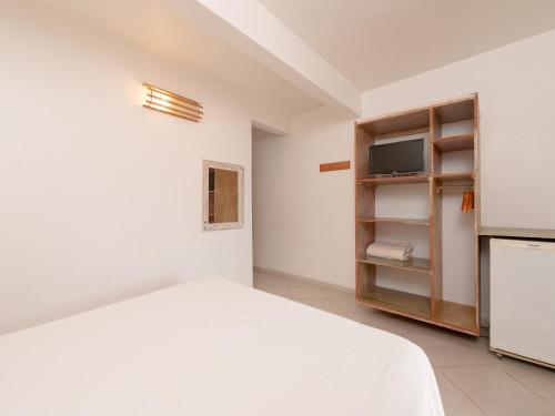 a white bedroom with a bed and a tv at Pousada Perequê in Ilhabela