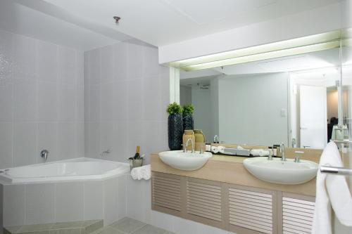a bathroom with two sinks and a tub and a mirror at The Lord Forrest Hotel in Bunbury