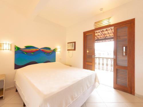 a bedroom with a white bed with a painting on the wall at Pousada Perequê in Ilhabela