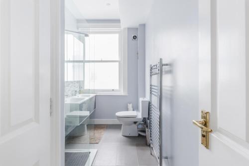 een badkamer met een toilet, een wastafel en een raam bij Live like a Londoner by TOWER BRIDGE in Londen