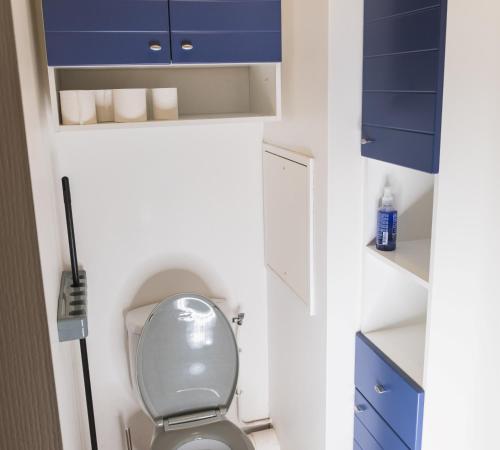 a bathroom with a white toilet and blue cabinets at Family Travel Paris 2 in Bussy-Saint-Georges