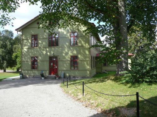 a large green house with red doors and a tree at Ronneby Brunnspark Vandrarhem och B&B in Ronneby