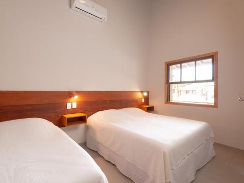 two beds in a hotel room with a window at Pousada Perequê in Ilhabela