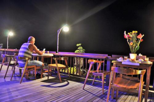 a man sitting at a table in a restaurant at Ocean Terrace Suite And Spa Luxury in Nusa Penida
