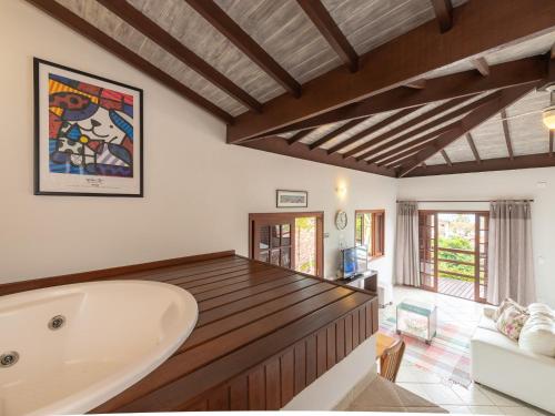 a bathroom with a tub and a living room at Pousada Perequê in Ilhabela