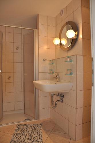 a bathroom with a sink and a shower with a mirror at Ferienwohnung Richter in Bad Schandau