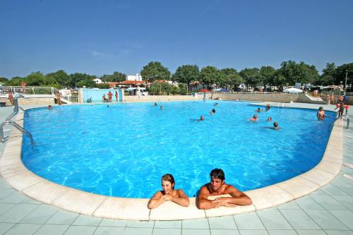 dos personas en una gran piscina en Naturist Mobile Homes Eden in FKK Ulika, en Poreč