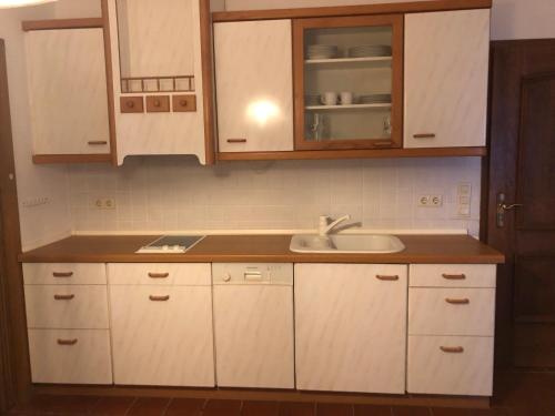 a kitchen with white cabinets and a sink at Landhotel Gasthof Zur Krone in Leidersbach