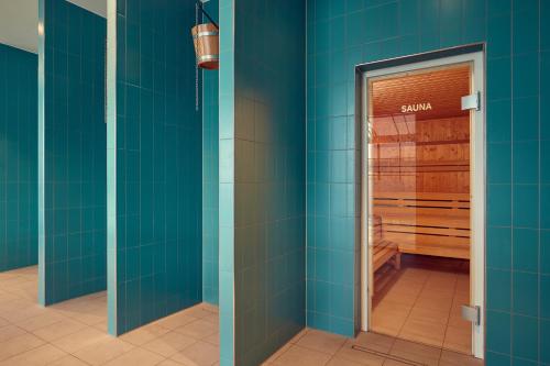 a bathroom with blue tiled walls and a sauna at Corendon Urban Amsterdam Schiphol Airport Hotel in Badhoevedorp
