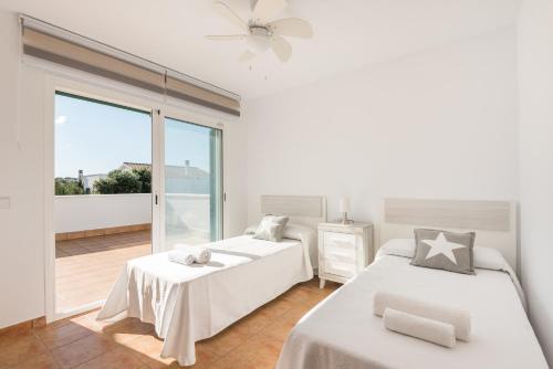 um quarto branco com 2 camas e uma varanda em Villa LaCalma em Es Mercadal