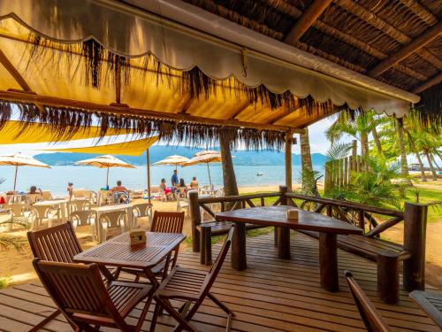 a wooden deck with tables and chairs on the beach at Pousada Perequê in Ilhabela
