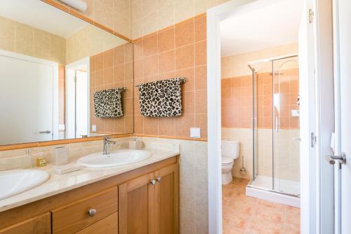 uma casa de banho com 2 lavatórios e um chuveiro em Villa LaCalma em Es Mercadal