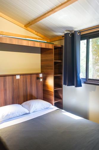 une chambre avec un lit avec une tête de lit en bois dans l'établissement Huttopia Lac de la Siauve, à Lanobre