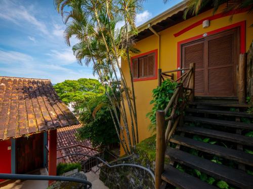 a yellow house with stairs and a palm tree at Pousada Perequê in Ilhabela