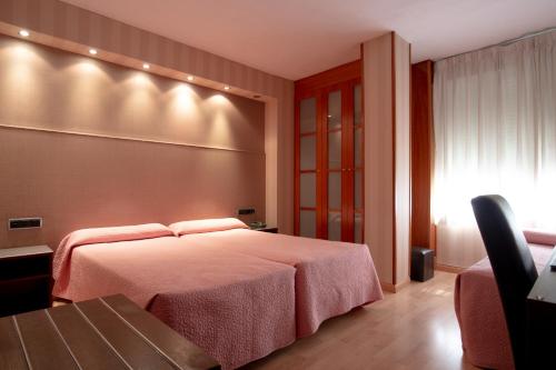 a bedroom with a bed and a table and a chair at Hotel Villa de Barajas in Madrid
