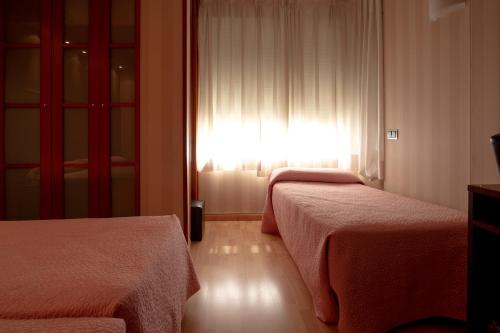 a hotel room with two beds and a window at Hotel Villa de Barajas in Madrid