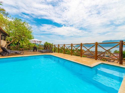 a large blue swimming pool with a wooden fence at Pousada Perequê in Ilhabela
