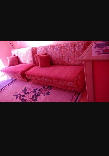 ein rosafarbenes Sofa in einem Zimmer mit einem Tisch in der Unterkunft Apartman S in Palisat