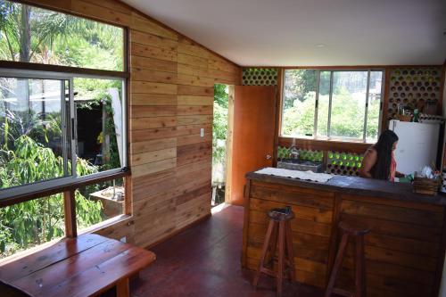 a kitchen with wooden walls and windows and a woman in the kitchen at Choclo in La Paloma