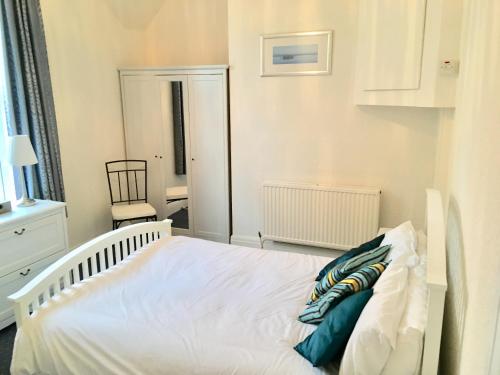 a bedroom with a white bed and a chair at Woodlands Holiday Apartments in Lytham St Annes