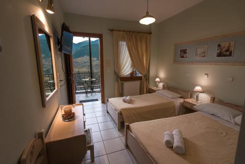 a hotel room with two beds and a balcony at Το Ηλιοβασίλεμα in Méga Khoríon