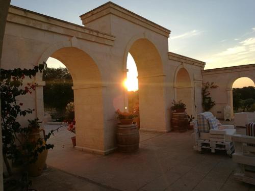 an outdoor patio with arches and a sunset in the background at Agriturismo I Pozzetti in Savelletri di Fasano