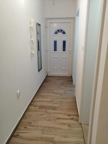 a hallway with a white door and a wooden floor at Apartments Purkovic in Vodice