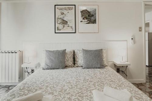 a white bedroom with a large bed and two tables at “Ivory house”with sea view in Manarola