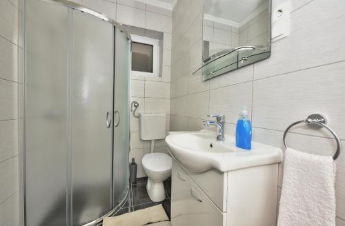 a white bathroom with a sink and a shower at Apartments Song of Joys in Makarska