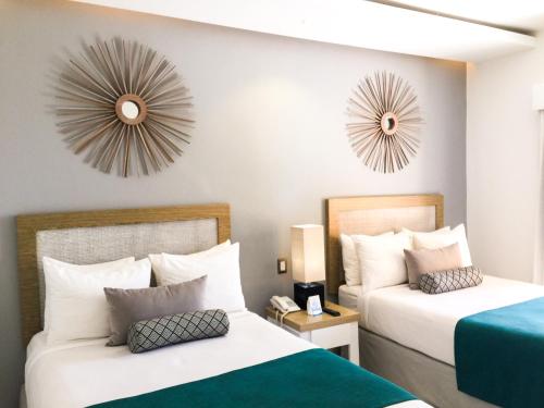 two beds in a hotel room with clocks on the wall at Casa Marina Beach & Reef All Inclusive in Sosúa