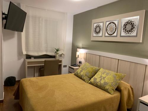 a small bedroom with a bed and a desk at Hotel Herreros in Castellón de la Plana