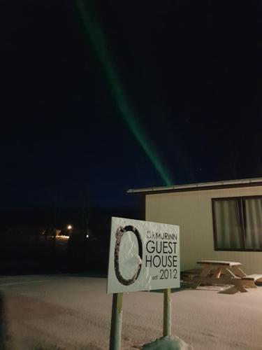 a sign in front of a guest house at night at Ormurinn Guesthouse in Egilsstadir