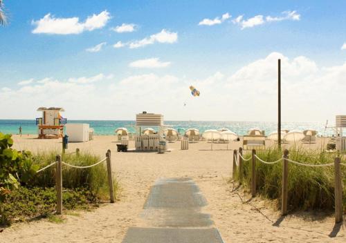 
a beach area with a beach chair and a boat on the beach at Hotel Breakwater South Beach in Miami Beach
