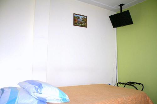 a bedroom with a bed and a television on the wall at Hostel Casa Alb in Bogotá