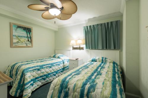 a bedroom with two beds and a ceiling fan at Sands Beach Club in Myrtle Beach