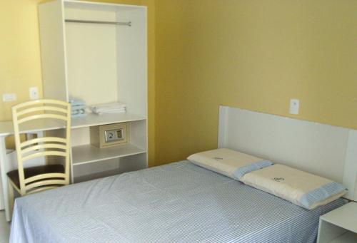 a small bedroom with a bed and a chair at Pousada NS Fátima in Fortaleza