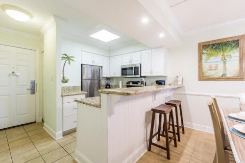 a kitchen with white cabinets and bar stools at Sands Beach Club in Myrtle Beach