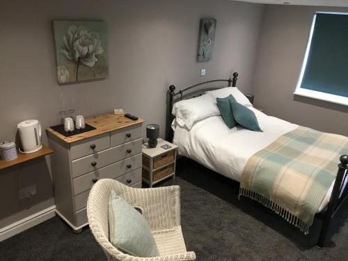 a bedroom with a bed and a dresser and a chair at Linden Tree Holiday Apartments in Thirsk