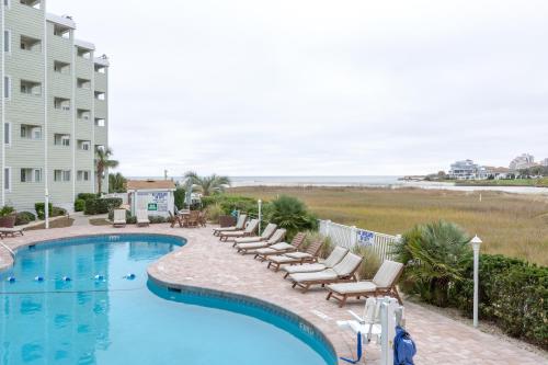 a swimming pool with lounge chairs and the beach at Sands Beach Club in Myrtle Beach