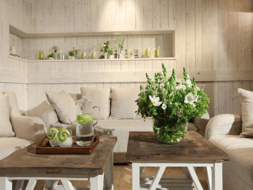 a living room with a vase of flowers on two tables at Spa & GolfResort Weimarer Land in Blankenhain