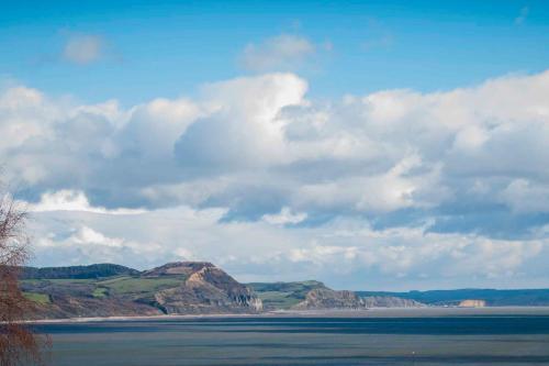 a large body of water with mountains in the background at Silver View-Spa Hot Tub-Beautiful Sea Views-Free Parking- Central Lyme Regis in Lyme Regis