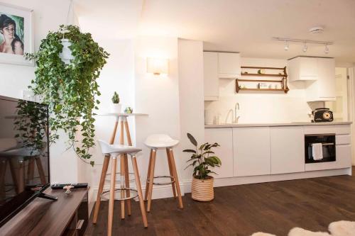 a kitchen with white cabinets and stools in a room at Silver View-Spa Hot Tub-Beautiful Sea Views-Free Parking- Central Lyme Regis in Lyme Regis
