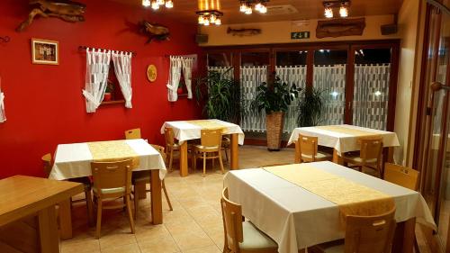 a restaurant with white tables and chairs and red walls at Gostišče Vančar in Bovec