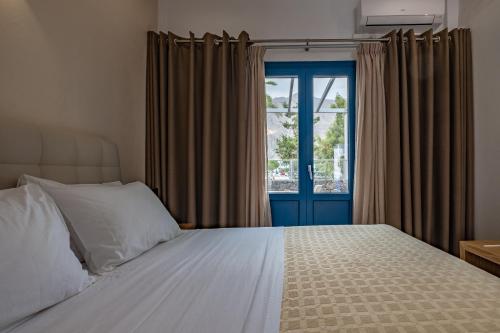 a bedroom with a bed and a blue door at Tristhenia in Perissa