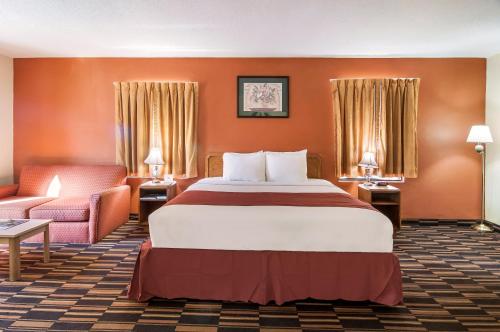 アービントンにあるRed Carpet Inn Newark - Irvington NJの大きなベッドと椅子が備わるホテルルームです。