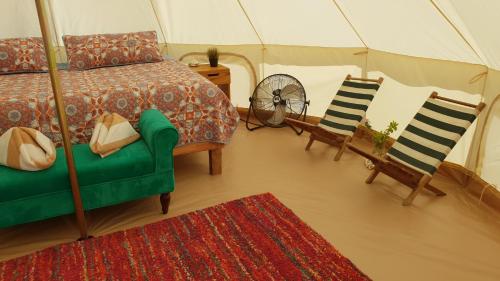 a bedroom with a bed and two chairs and a tent at ChiloChill Glamping Resort in La Ventana