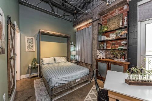 a bedroom with a bed and a brick wall at Green Door Lofts -Magnolia Loft, Silos/Downtown in Waco